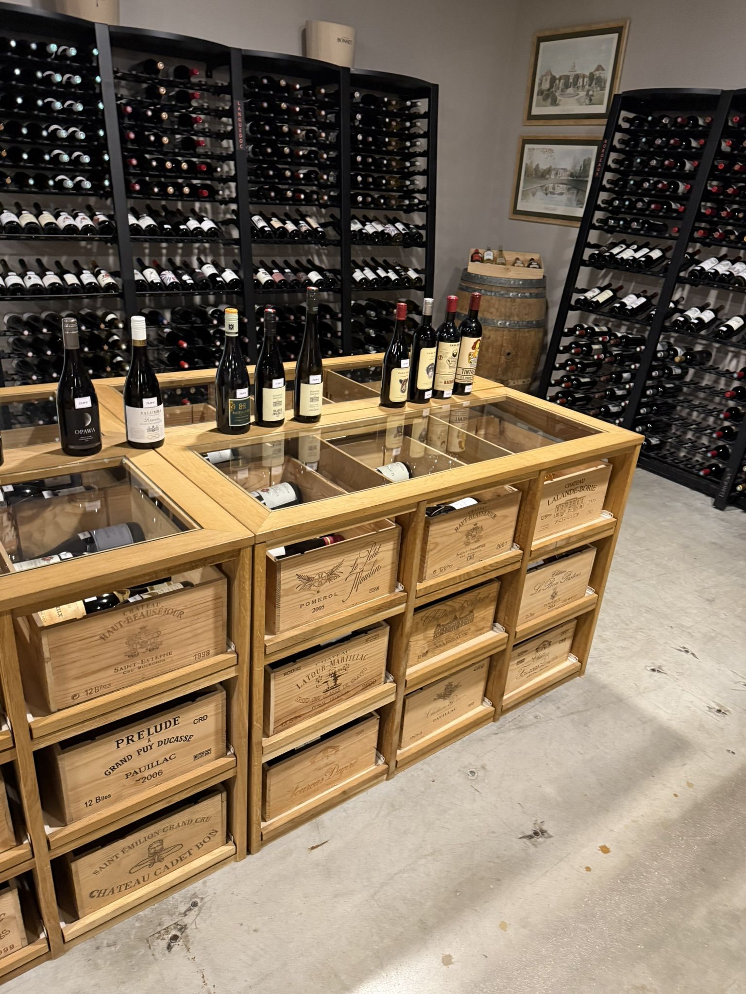 La cave à vins : casiers noirs remplis de bouteilles et caisses en bois de grands crus