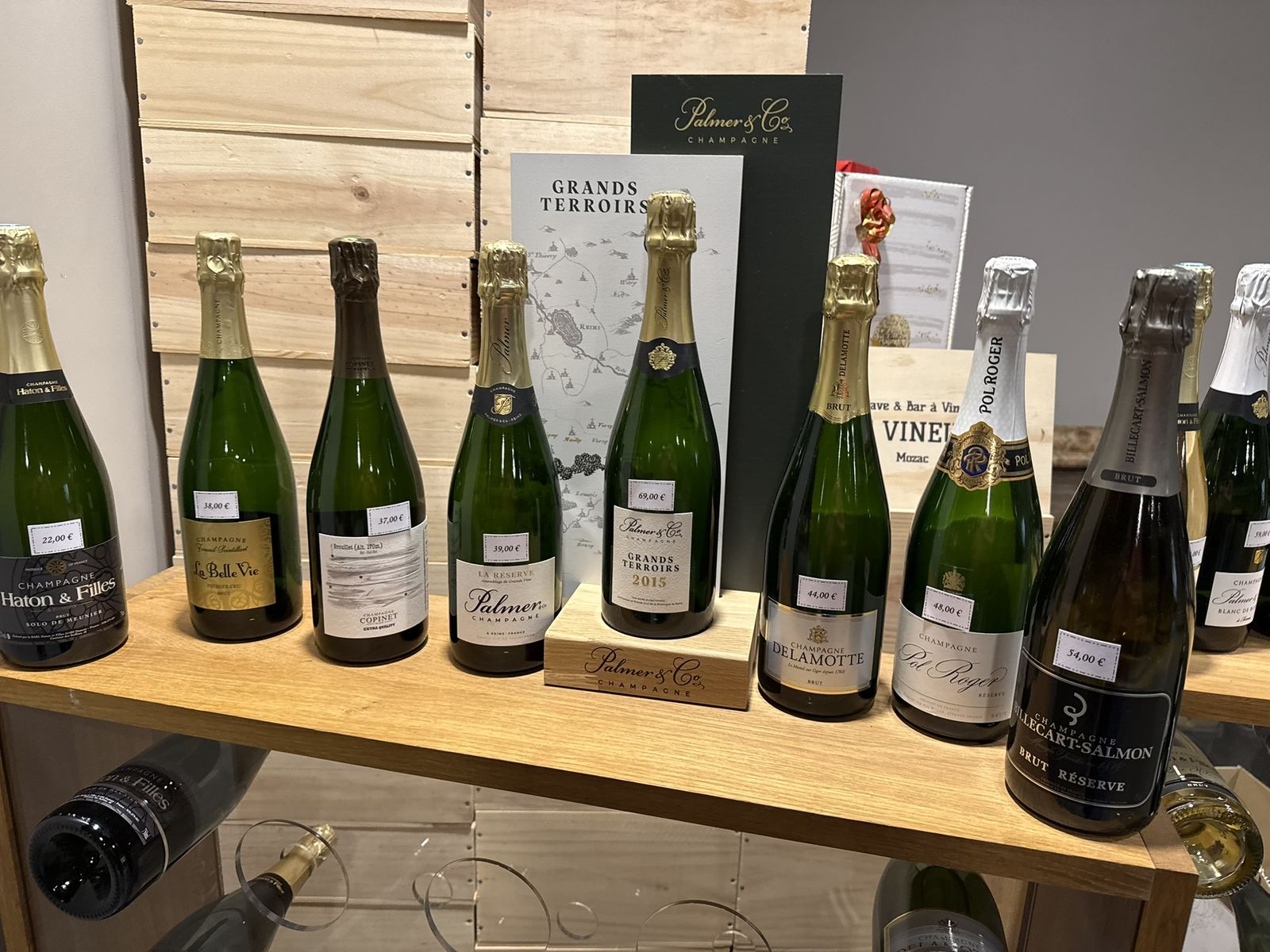 Le rayon champagnes : bouteilles alignées sur des étagères en chêne clair