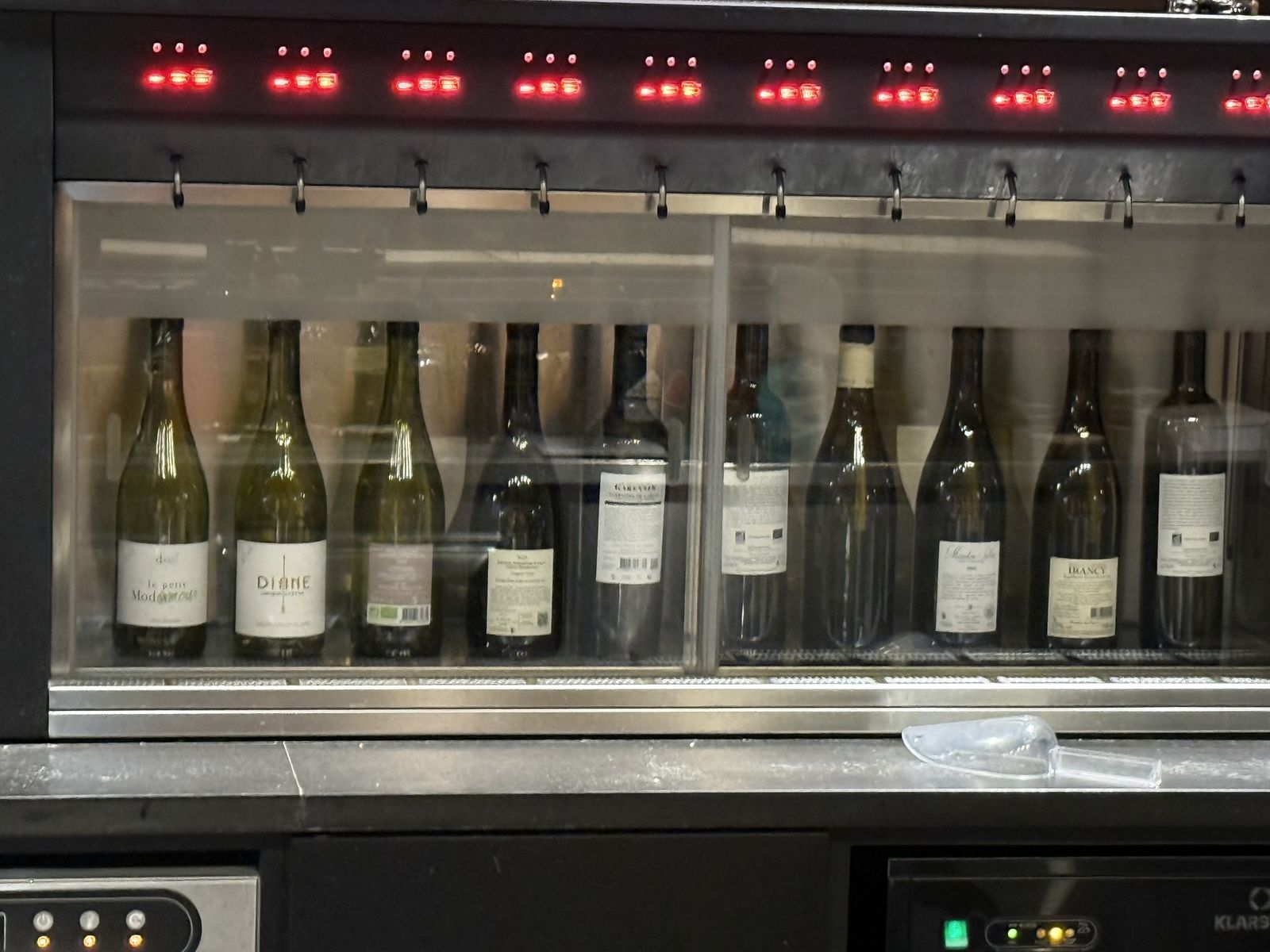 La machine à vin au verre, chargée d'une dizaine de bouteilles, blancs à gauche et rouges à droite